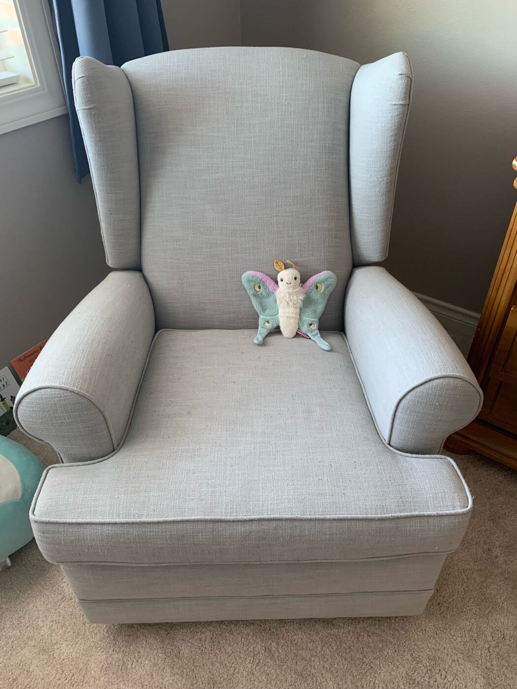 A grey armchair with a stuffed moth sitting on the seat