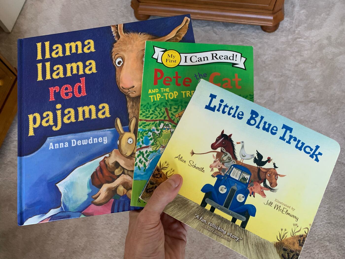 Llama Llama Red Pajama, Pete the Cat and Little Blue Truck held in one hand